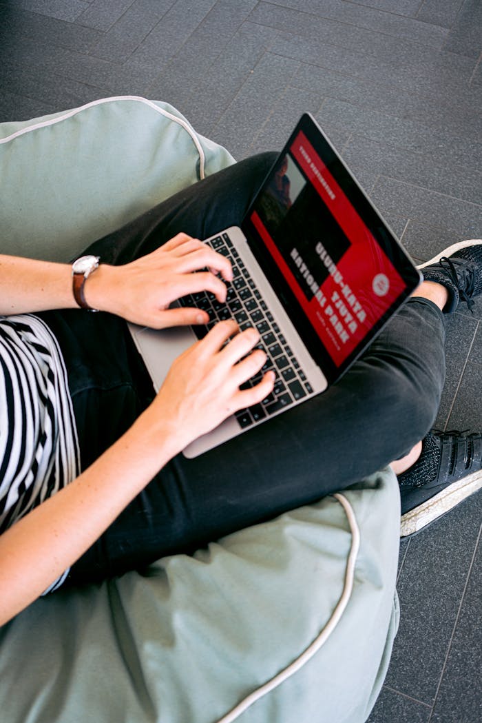 Home Person working remotely on a laptop while sitting comfortably on a beanbag chair indoors.