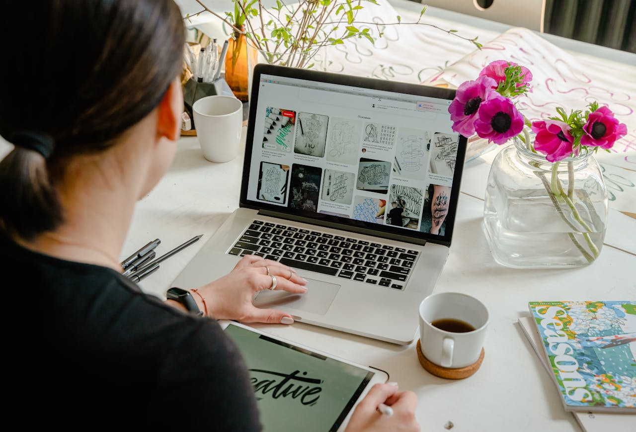 Home Woman in a creative workspace using a laptop and tablet for calligraphy. Artistic and tech-driven environment.